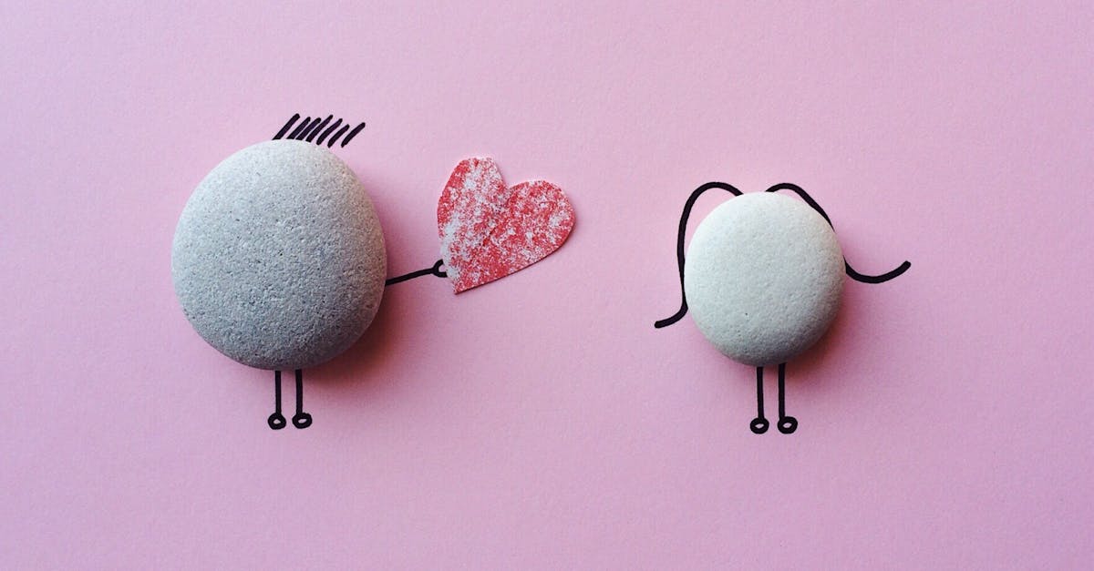 Une pierre tend un cœur à une autre sur fond rose - symbole d'amour offert malgré la fierté